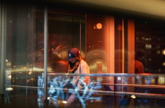 Anonymous person passing illuminated glass at night