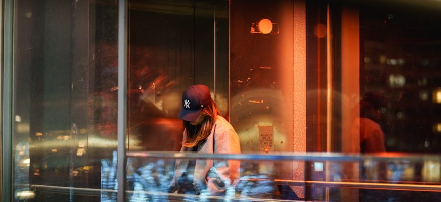 Anonymous person passing illuminated glass at night